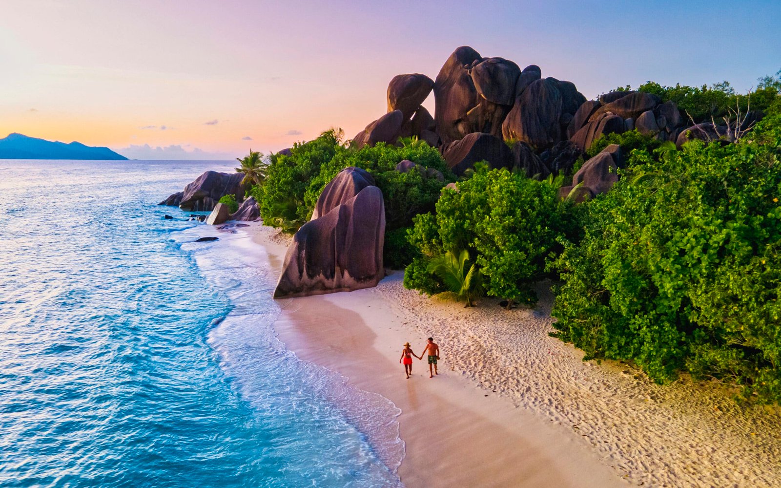 Anse Source d'Argent beach, La Digue Island, Seyshelles, Drone aerial view of La Digue Seychelles bird eye view, couple men and woman walking at the beach during sunset at a luxury vacation