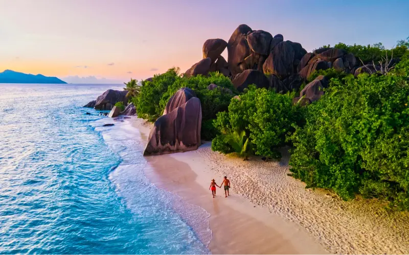 Anse Source d'Argent beach, La Digue Island, Seyshelles, Drone aerial view of La Digue Seychelles bird eye view.of tropical Island, couple men and woman walking at the beach during sunset at a luxury vacation